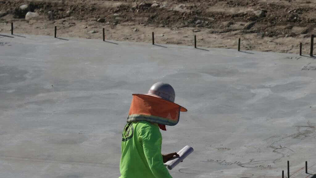 Engineer inspecting concrete slab at construction site in daylight.